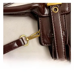 Detail of vintage gold swivel hook and stitching on dark brown leather shoulder strap