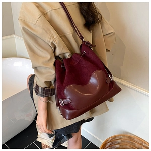 Détail d'un sac seau bordeaux à cordon avec texture suédée et anneaux métalliques sur mannequin
