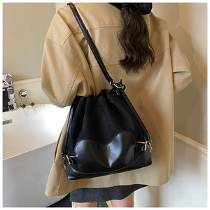 Vue détaillée du sac seau noir avec patch cœur porté par un mannequin dans un décor épuré
