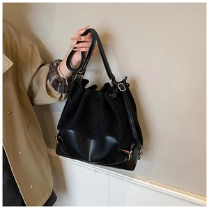 Détail du sac seau noir à cordon avec patch cœur en cuir et boucle en métal argenté