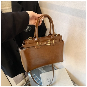 Close-up of caramel brown vintage tote bag with gold buckle detail and fine leather texture