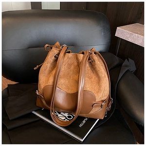 Détail d'un sac seau marron avec cordon et mélange de textures en daim et cuir lisse