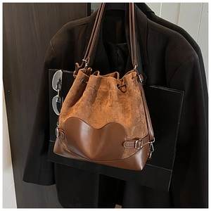 Détail du sac seau en daim marron avec empiècement cœur en cuir et double bandoulière