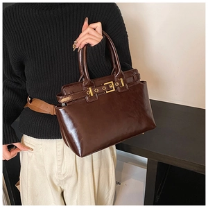 Detail shot of vintage dark brown glossy leather handbag with gold metal buckles and handles