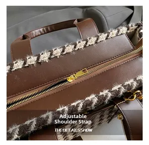 Detail view of brown leather tote bag with houndstooth trim and golden metal zipper