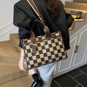Detail of checkered tote bag with gold metal twist lock and leather trim accessories