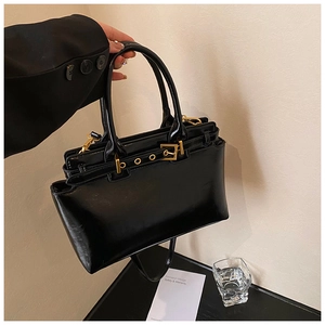 Detail of black glossy leather tote bag with elegant gold hardware and sturdy handle