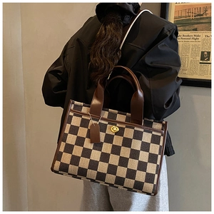 Detail of vintage checkerboard tote bag with brown leather handles and golden twist lock
