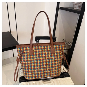 Detail of multi-color plaid wool tote bag with premium brown leather straps and rivets