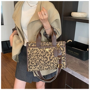 Close-up of leopard print tote bag with striped shoulder strap and metal turn-lock