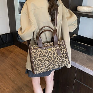 Detail of leopard jacquard tote bag with dark brown leather trim and golden twist lock