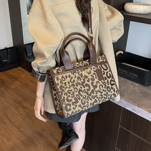 Close-up of leopard print tote bag with brown leather handles and golden twist lock