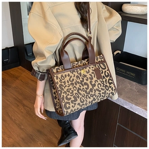 Close-up of leopard canvas tote with brown leather handles and gold twist lock detail