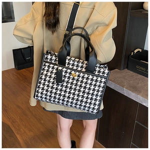 Detail of leopard plaid tote bag with black leather handles and gold metal clasp hardware