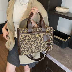 Close-up of leopard print tote with brown leather trim and golden turnlock closure