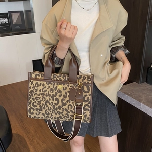 Detail of leopard print tote bag with brown leather handles and adjustable woven strap
