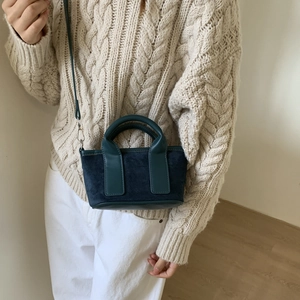 Mini sac bandoulière bleu sarcelle porté avec un pull en maille beige élégant