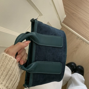 Vue détaillée du sac à main bleu marine en daim avec garniture en cuir et boucles