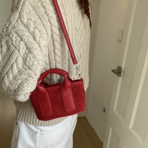 Détail du petit sac rouge carré montrant la texture toile et cuir sur un mannequin
