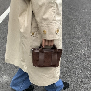 Détail d'un petit sac carré marron avec poignées texturées et bandoulière amovible