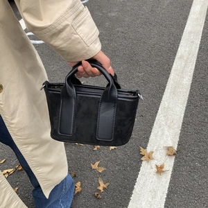Détail du sac cabas noir avec patchwork de toile et cuir dans un cadre urbain moderne