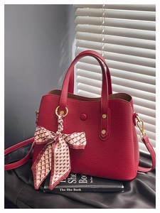 Detail of red lychee leather tote with decorative silk scarf and gold metal hardware