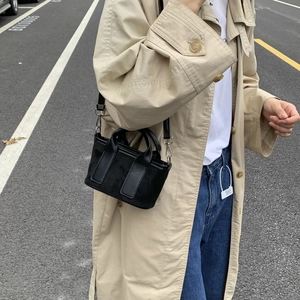 Photo de rue d'un mini sac noir en toile avec des crochets métalliques argentés