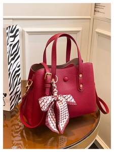 Detailed macro view of dark red lychee grain leather handbag with silk scarf on the handle