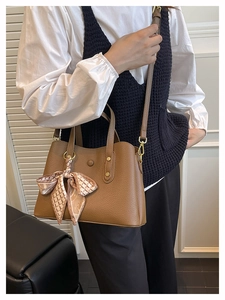 Brown litchi grain leather handbag with decorative silk scarf shown on model