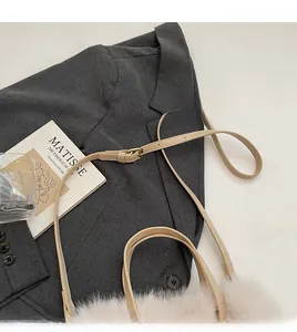 Detail eines beigen Riemens mit goldener Schnalle an einer rosa Plüschtasche