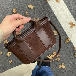 Détail d'un mini sac à main carré marron foncé en daim et cuir avec bandoulière