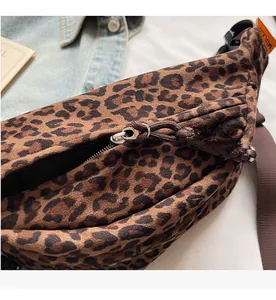 Détail de sac banane léopard avec fermeture argentée et tirette tissée sur denim bleu