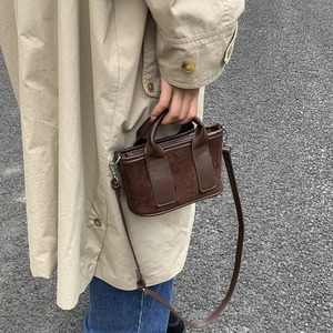 Détails de texture d'un mini sac bandoulière en daim marron avec bordure en cuir lisse