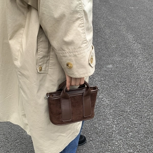 Détail du mini sac marron foncé en daim et toile porté avec un trench pour un look mode