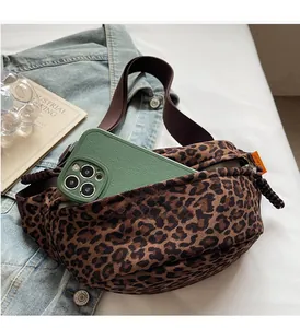Détail d'un sac banane léopard avec bandoulière marron porté sur une veste en jean