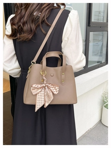 Detail of coffee brown lychee leather handbag with decorative checkered silk scarf and strap