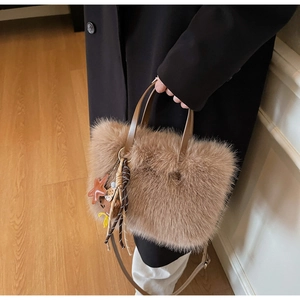 Detail der braunen Plüschtasche mit Sternanhänger und Ledergriff auf einem schwarzen Mantel
