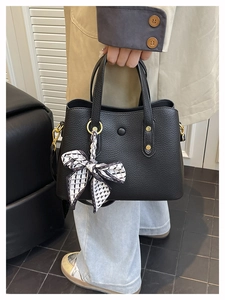 Detail of black pebbled leather tote bag with silk scarf accent and gold hardware