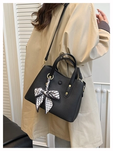Detail of black lychee grain leather handbag with silk scarf and decorative metal studs