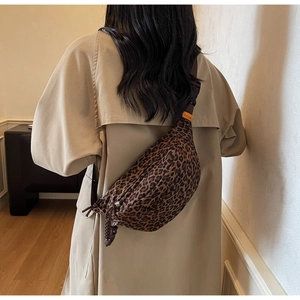 Détail du sac banane léopard avec bandoulière réglable et étiquette de marque orange