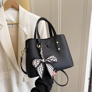 Detail of black pebbled leather tote with gold hardware and silk scarf on the handle
