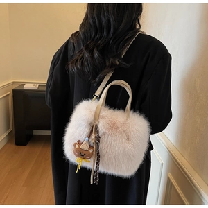 Detail einer Plüsch-Schultertasche mit Bärenanhänger und gewebtem Seilknoten-Akzent