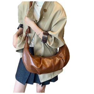 Brown pleated croissant shoulder bag with knotted strap shown on a casual blazer outfit
