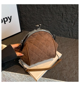 Close-up of brown quilted suede shell bag with vintage metal kiss lock and chain strap