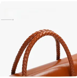 Close-up of caramel brown tote bag featuring intricate cross-braided leather handles