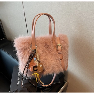 Detailansicht der rosa Plüschtasche mit Bärenanhänger auf einem Designbuch