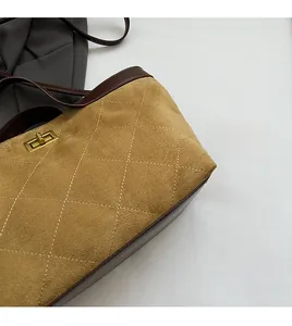 Detail of tan suede bucket bag with quilted stitching and gold swivel metal clasp