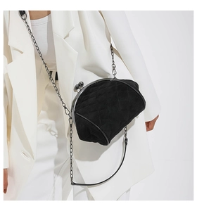 Close-up of black quilted shell bag with vintage metal clasp and fine chain strap