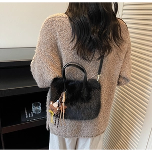 Detailansicht einer schwarzen Plüsch-Umhängetasche mit kleinem Bären-Anhänger an einem Model