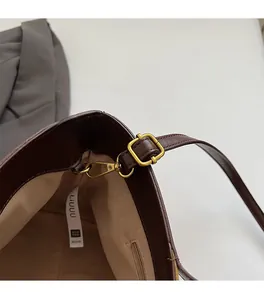 Detailed close-up of dark brown bucket bag featuring vintage gold hardware and adjustable strap